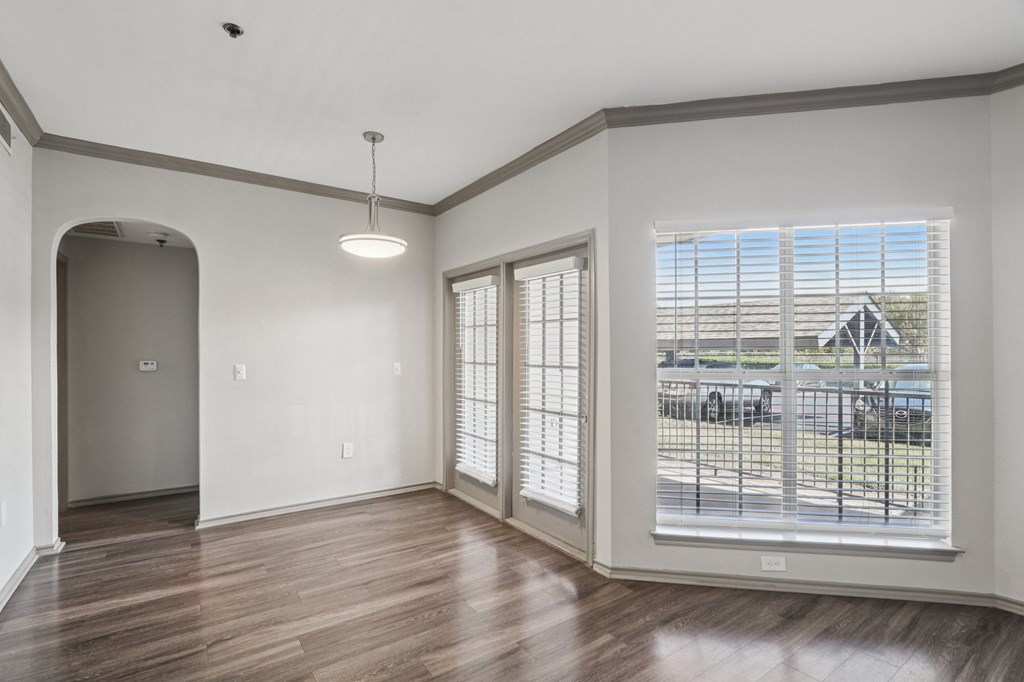 A room with a wooden floor and a large window with blinds.