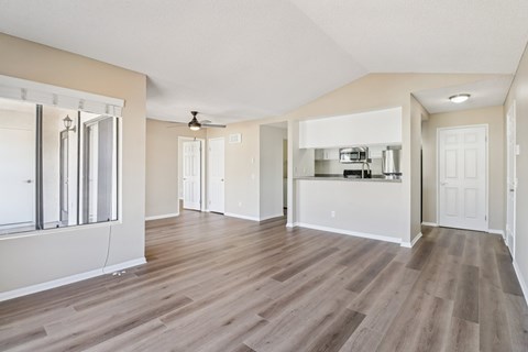 A spacious room with wood flooring and a ceiling fan.