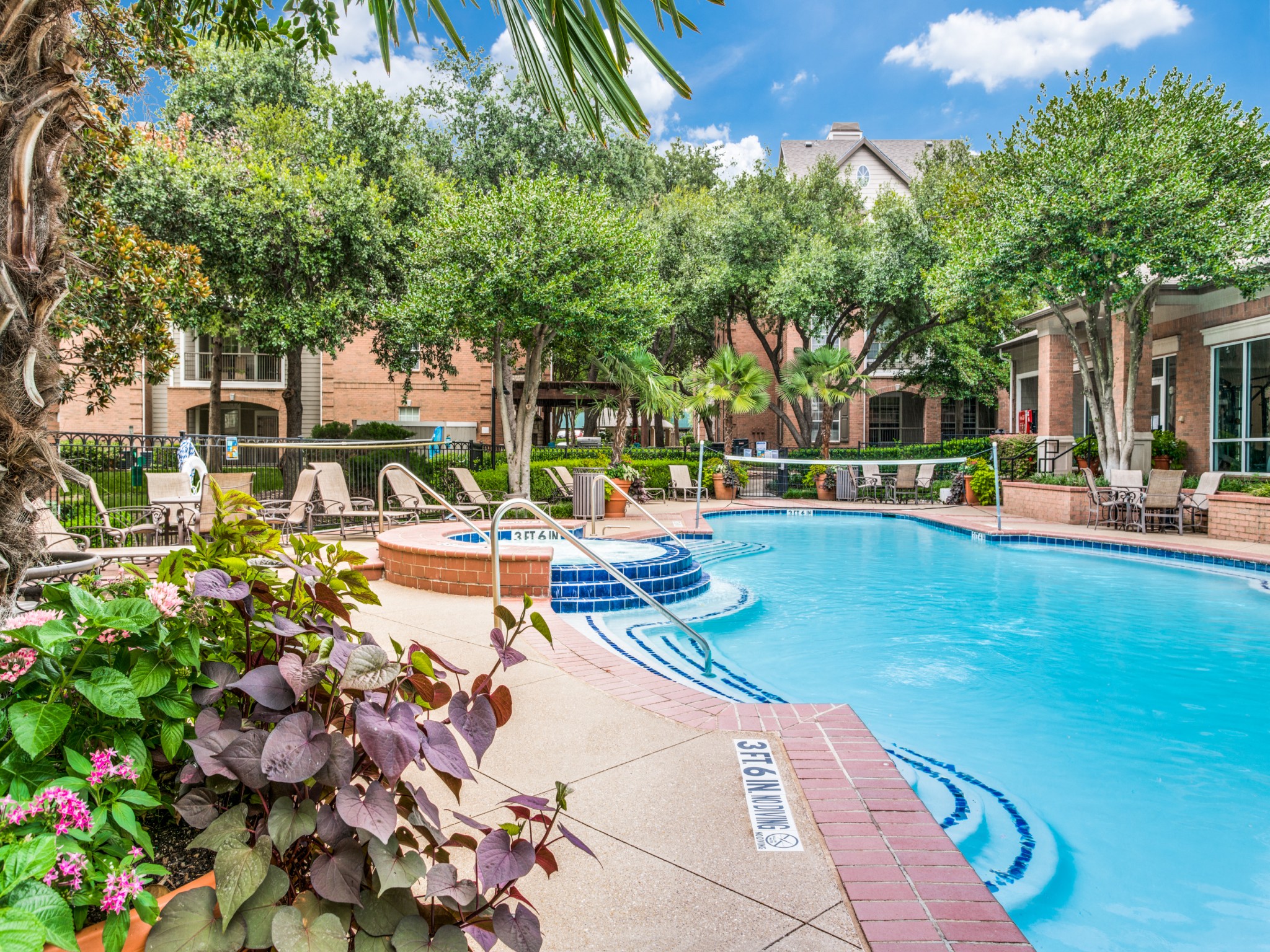 Apartments in North Dallas for Rent-Sparkling Swimming Pool With Volleyball Net Surrounded by Lounge Chairs and Seating