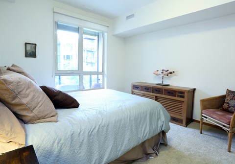a bedroom with a bed and a dresser and a window