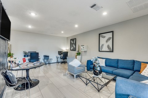 A living room with a blue couch and a glass table.