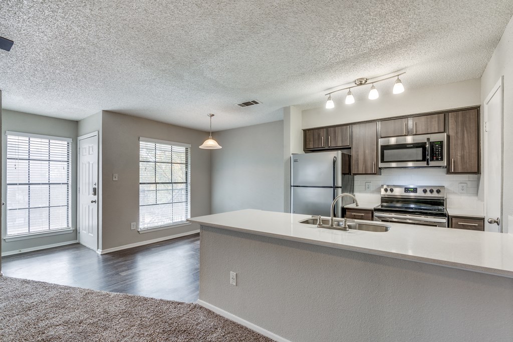 a kitchen with a white counter top and a stainless steel refrigerator