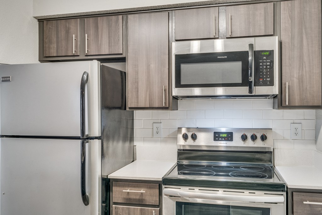 an empty kitchen with stainless steel appliances and wooden cabinets