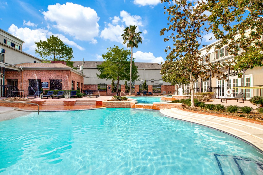 A large swimming pool in the middle of a courtyard surrounded by trees and buildings.