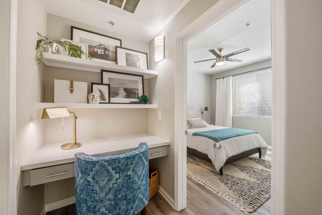 a bedroom with a bed and a desk and a ceiling fan