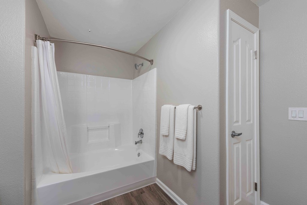 a white bathroom with a tub and shower and white towels