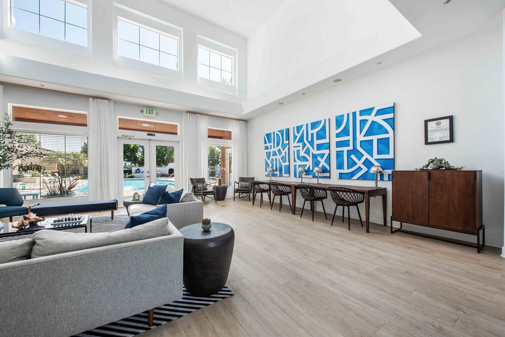 A modern living room with a grey sofa and a large abstract painting on the wall.