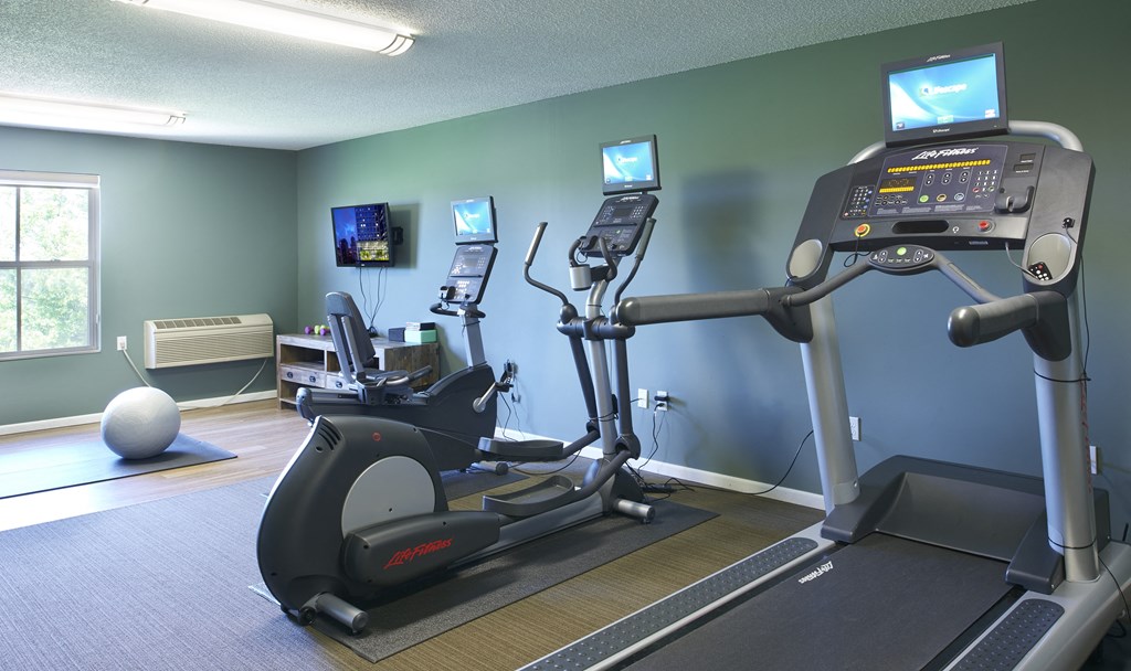 a gym with exercise equipment and televisions on the wall