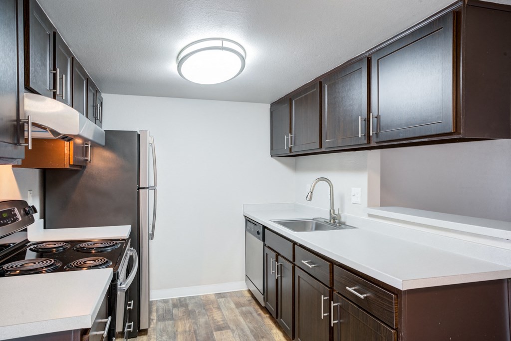 a kitchen with dark cabinets and white countertops