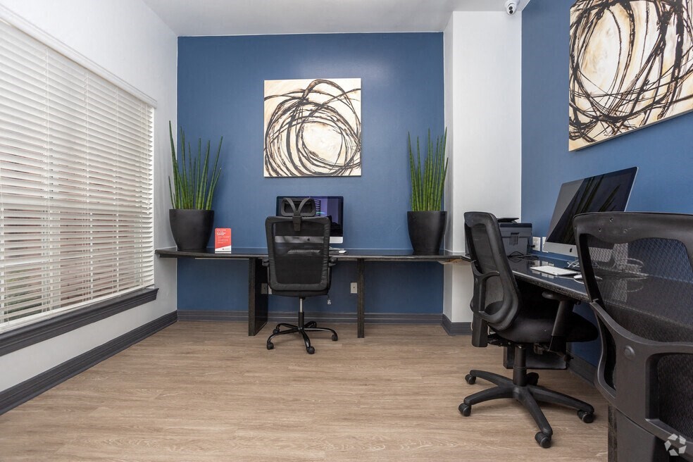 an office with two desks and chairs and a window