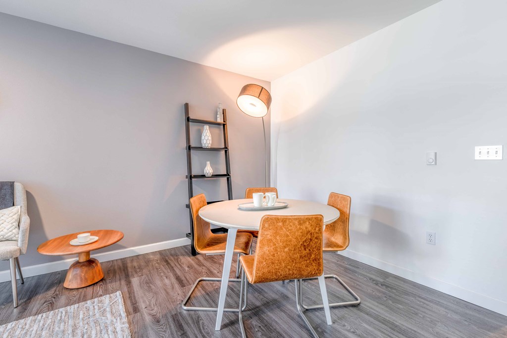a dining area with a round table and orange chairs