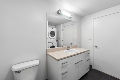 A white bathroom with a washer and dryer built in.