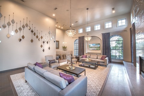 A living room with a grey couch and a chandelier.