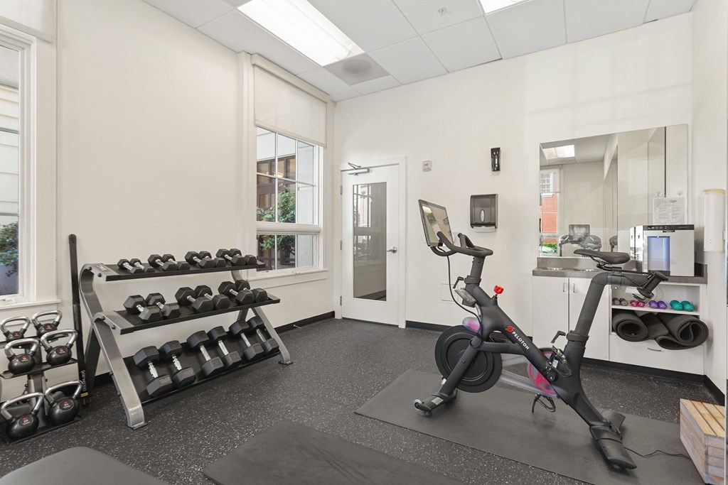 a gym with exercise equipment and dumbbells on the wall