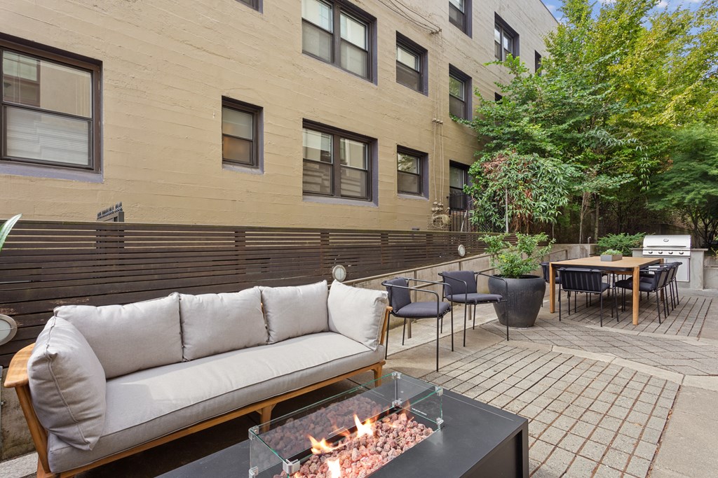 Two-Bedroom Apartments in Nob Hill, Portland, OR - The Cordelia - Patio with Fire Pit, Couch, Table, and Chairs with a BBQ Grill Area.