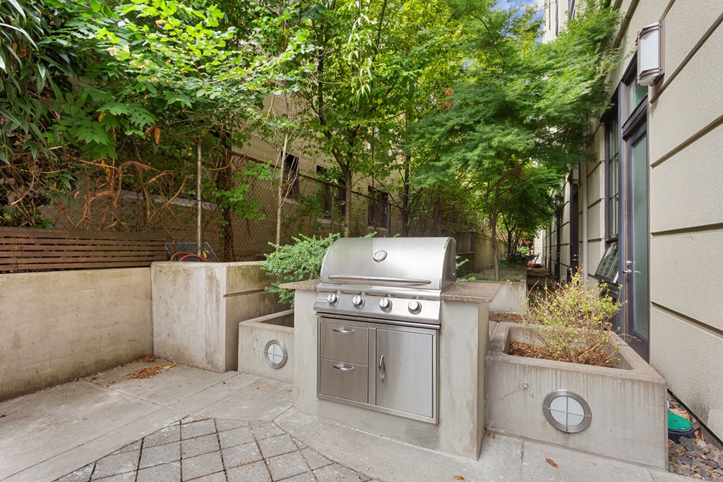 a backyard with a stainless steel grill on the side of a house