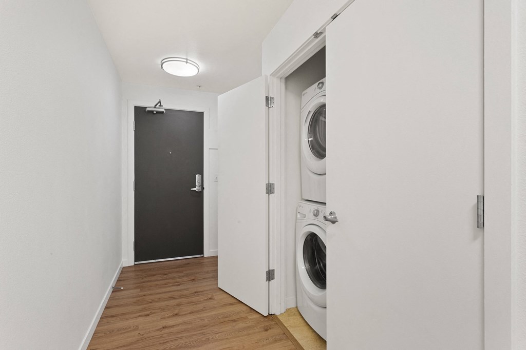 a washer and dryer in a white room with a black door