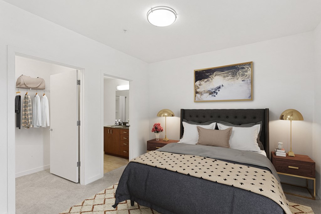 Nob Hill, Portland, OR, Apartments - The Cordelia - Bedroom with Oversized Closet, Brown Night Stands with Lights, Grey Bed with Decorative Area Rug, and Access to the Bathroom.