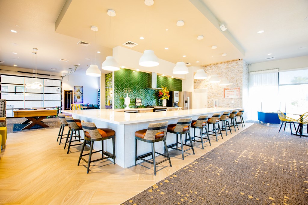 a long bar with chairs and a table in a lobby