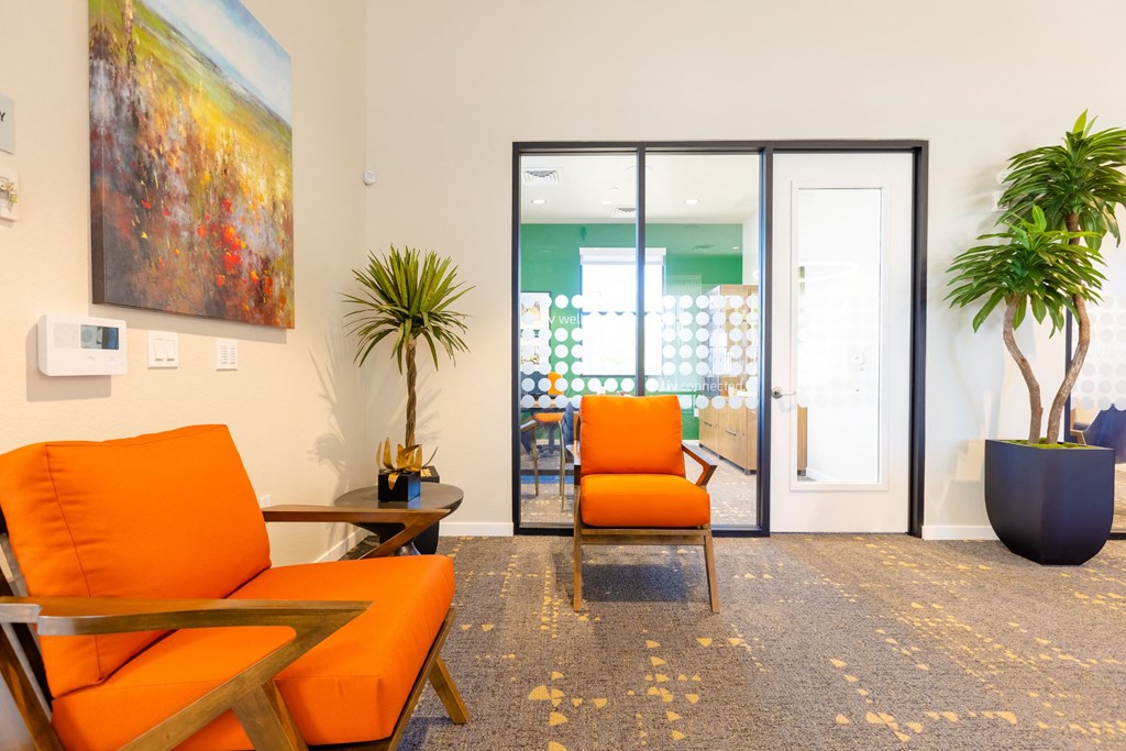 a living room with orange chairs and a sliding glass door