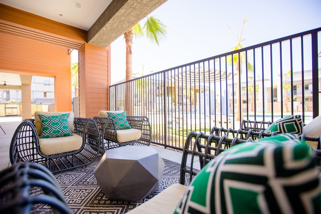 a living room with chairs and a table and a balcony with palm trees