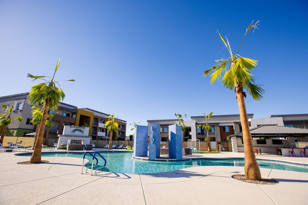 a swimming pool with palm trees and buildings in the background