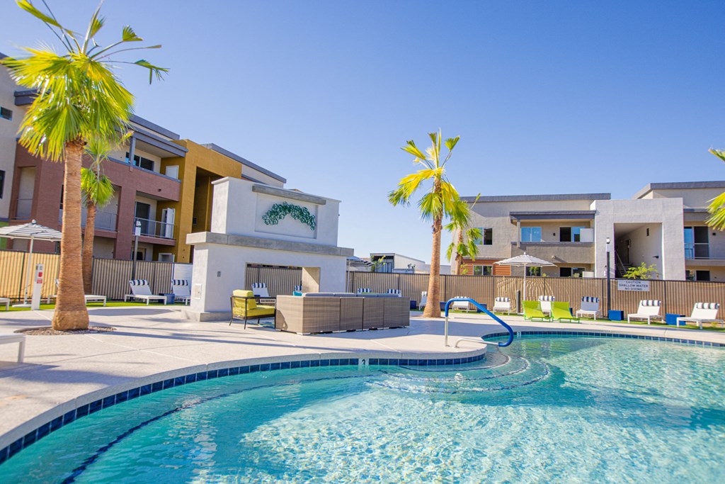a swimming pool with palm trees and apartments in the background