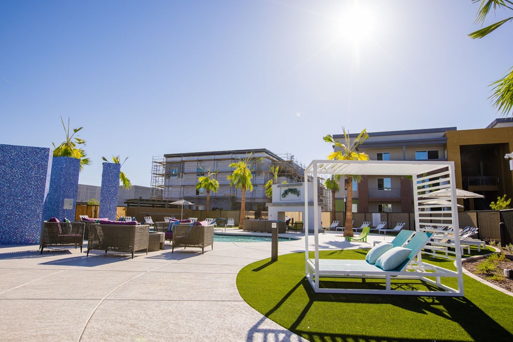 a patio with lounge chairs and a pool at a hotel with palm trees