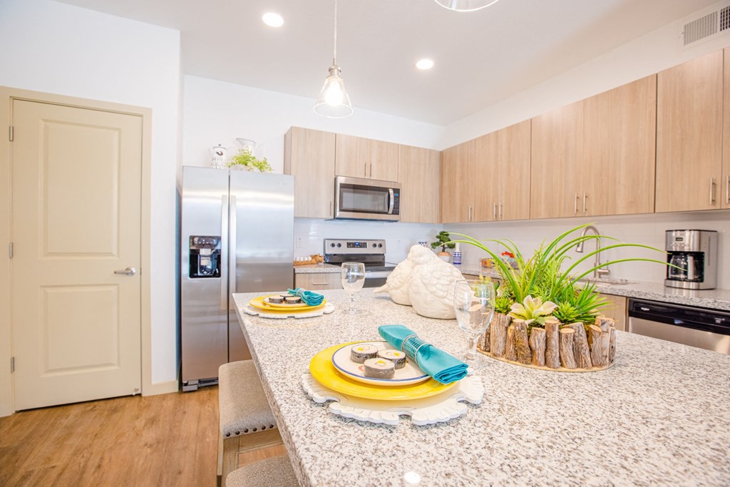 Pet-Friendly Apartments In Gilbert, AZ - Kitchen With Granite Countertops, Stainless Steel Appliances, Dishwasher, Tile Backsplashes, And Plank Flooring.