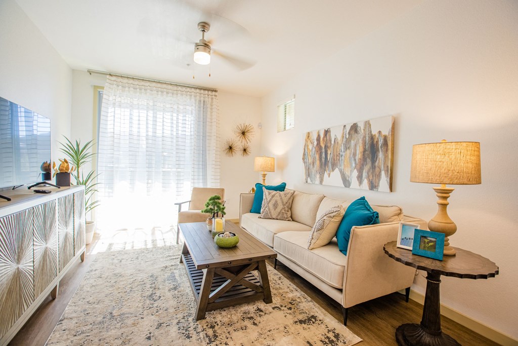 Apartments in Gilbert, AZ for Rent - Curve At Gilbert - Living Room With A Ceiling Fan, Plank Flooring, And A Sliding Glass Door To A Private Patio/Balcony