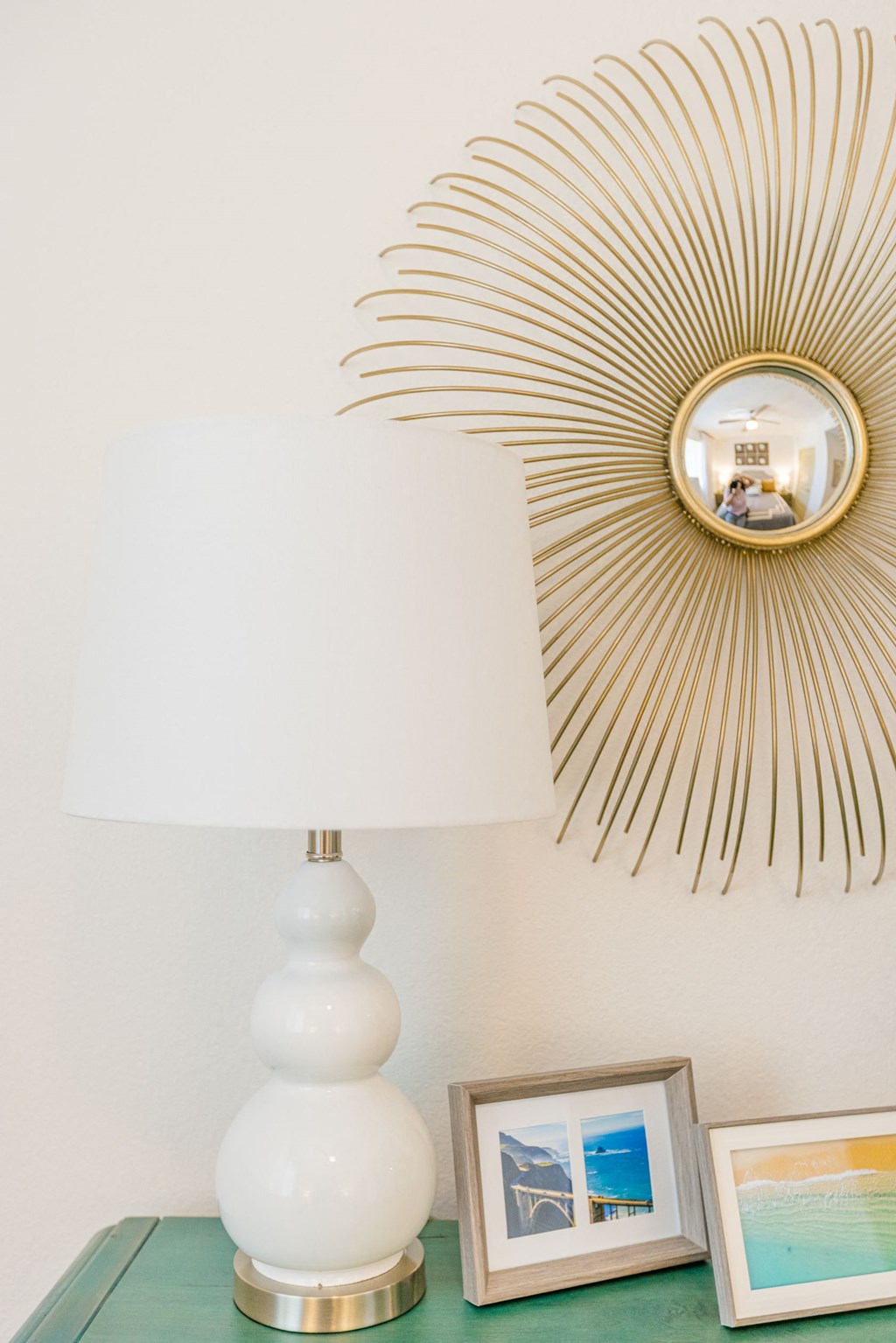 a white table with a lamp and a mirror on the wall