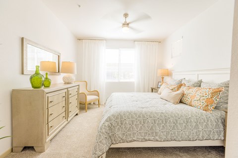 One BR Apartments in Gilbert AZ - Curve at Gilbert - An interior shot of the bedroom featuring a ceiling fan, window coverings, and plush carpeting