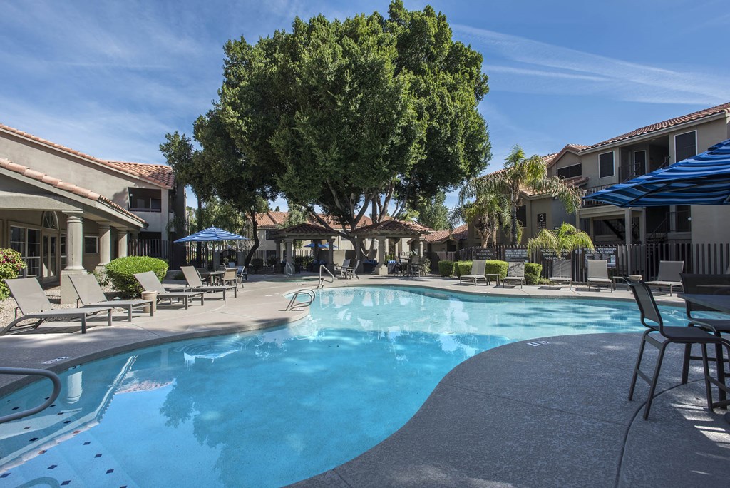 a large swimming pool with chairs and umbrellas at a resort