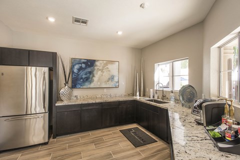 a kitchen with granite counter tops and a stainless steel refrigerator