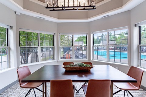 a dining room with a table and chairs with a view of a pool in the background