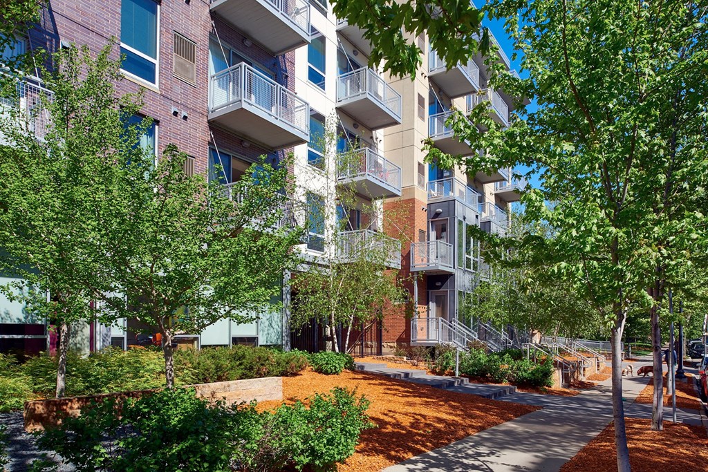 an apartment building with trees and a sidewalk