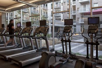 a row of treadmills in a gym with a large window