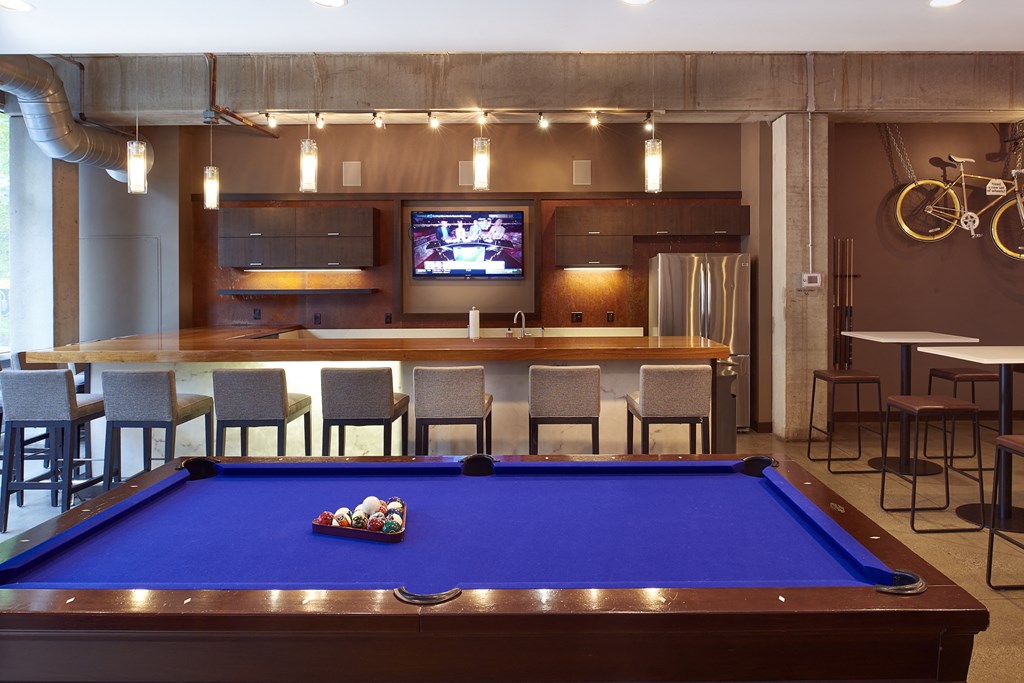 a pool table in a room with a bar and a tv