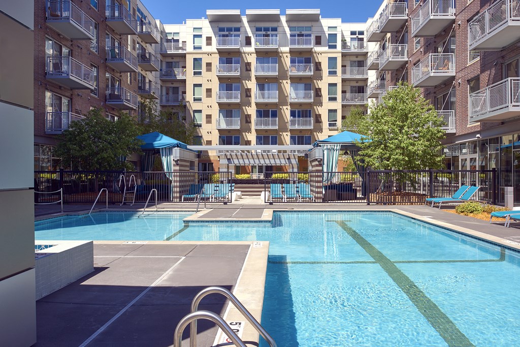 an apartment swimming pool with an apartment building in the background