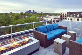 a rooftop patio with a blue couch and a fire pit