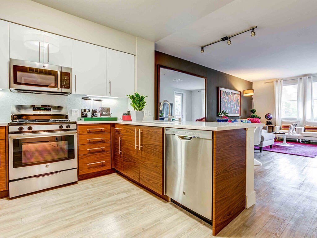 stainless steel appliances in apartment kitchens and wood inspired flooring.