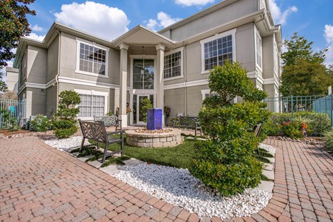 Luxury One-Bedroom Apartments in Houston, TX - The Maroneal - Exterior View of the Leasing Office with Benches, a Fountain, and Beautiful Landscaping