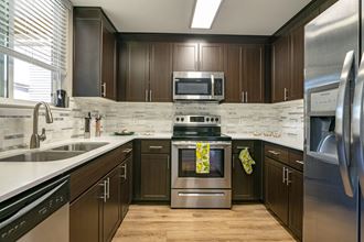 Wood floors, wood cabinets with stainless steel appliances in kitchen