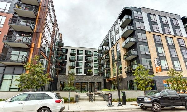 A modern apartment complex with cars parked in front.