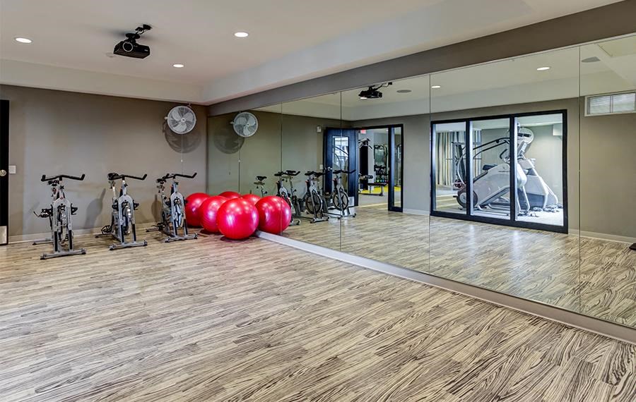 A room with a wooden floor and a glass wall with a reflection of a bicycle.