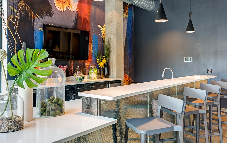 a kitchen with a long counter and chairs and a tv