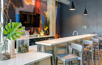 a kitchen with a long counter and chairs and a tv