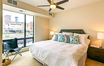 a bedroom with a large window and a ceiling fan