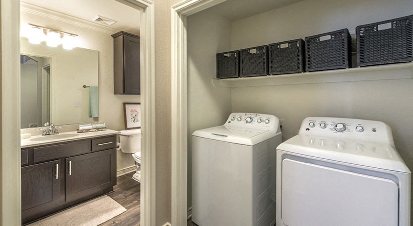a white washer and dryer in a laundry room with a sink and bathroom