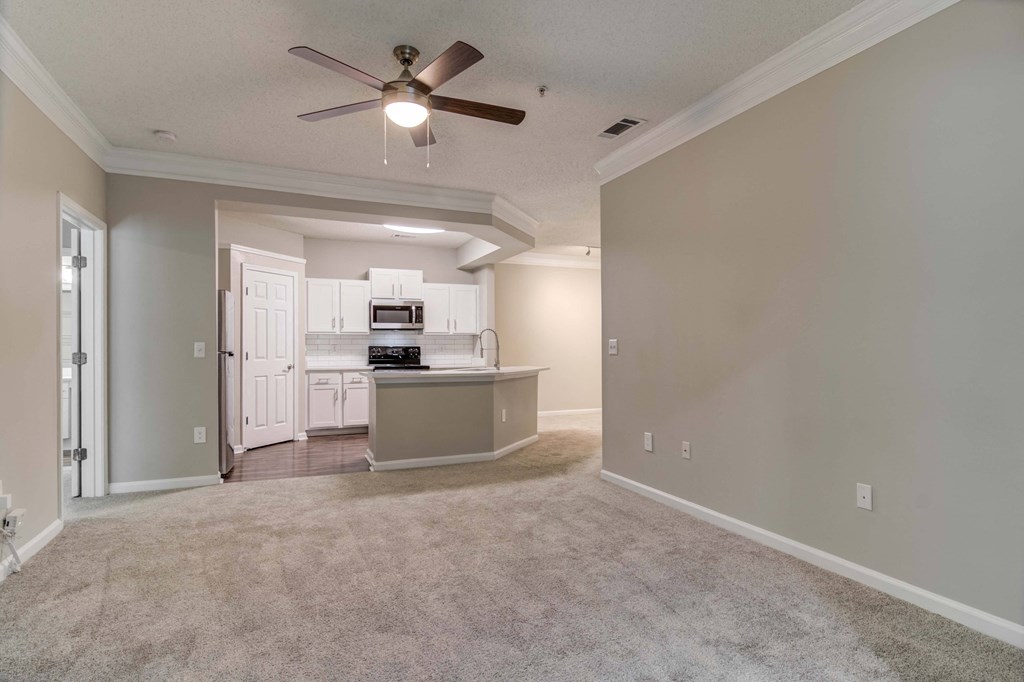 Woodstock, GA Apartments – Lea Woodstock – Living room with plush carpeting, ceiling fan and view of kitchen